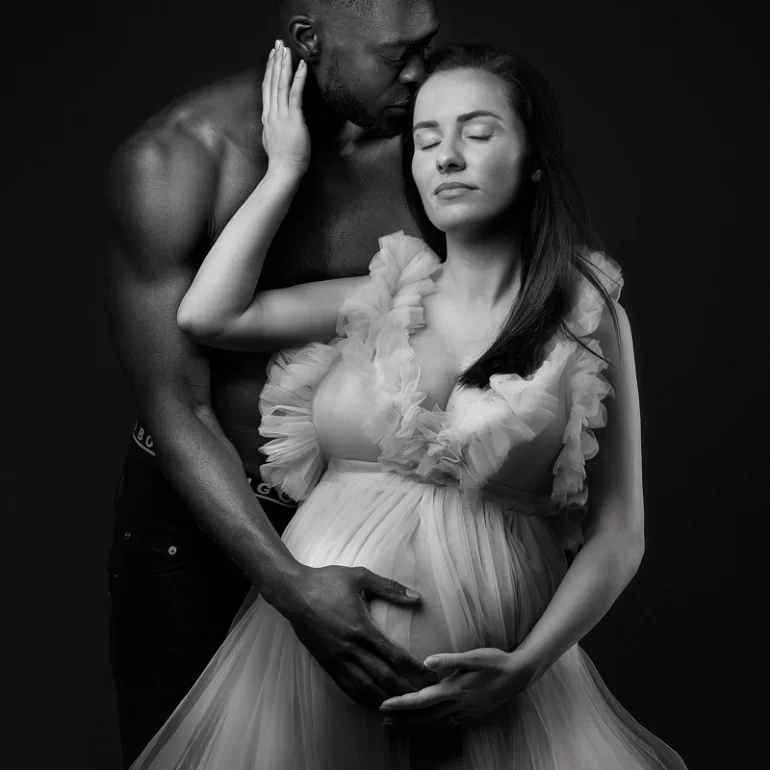 Maternity Photoshoot in North West London 20 B&W couple’s embrace; ruffled gown and protective forehead kiss.