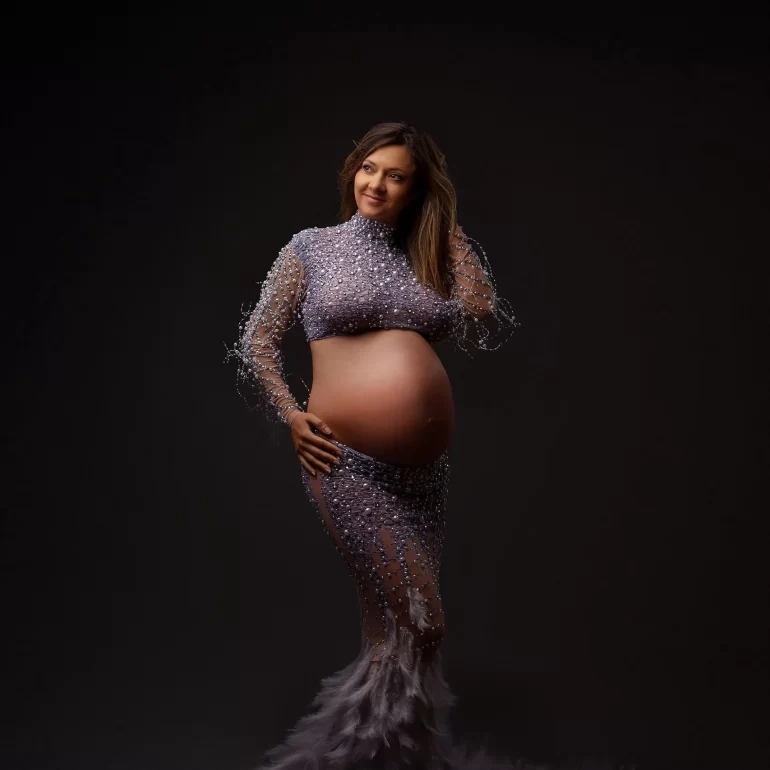Maternity Photoshoot in North West London 35 Lavender beaded gown with feathers; confident pose in dark studio.