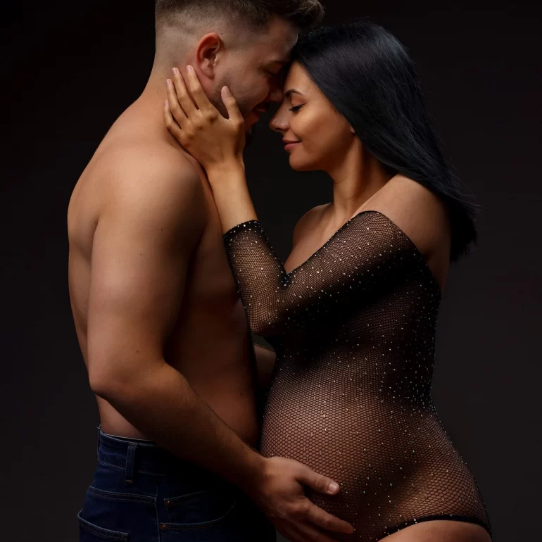 Maternity Photoshoot in North West London 42 Sheer black bodysuit; intimate forehead touch with partner; dark tones.