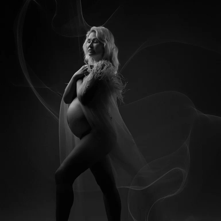 Maternity Photoshoot in North West London 47 B&W with sheer fabric and feather details; confident forward step.