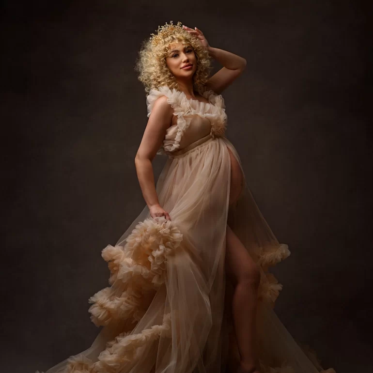 Maternity Photoshoot in North West London 9 Ruffled sheer beige gown and golden crown; confident expectant mother, dramatic light.