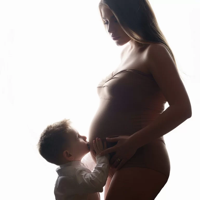 Maternity Photoshoot in North West London 54 Backlit silhouette of mother and young son; kiss on the belly.