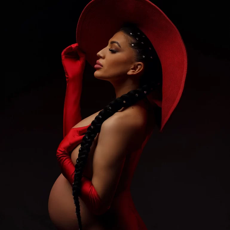 Maternity Photoshoot in North West London 14 Red hat and gloves, pearl braid; bold side‑profile of pregnant woman.