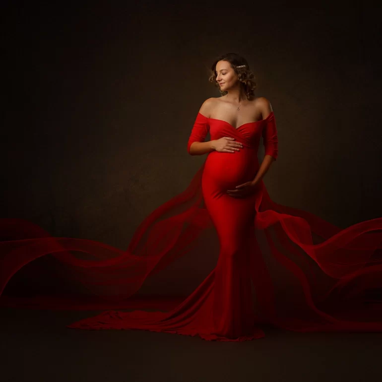 Maternity Photoshoot in North West London 95 Vibrant red, form‑fitting gown with sheer extensions; serene smile.