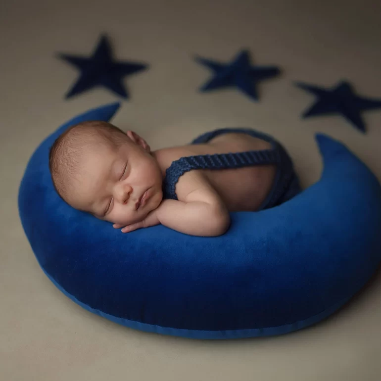 Newborn Photoshoot in North West London 26 Baby on deep‑blue moon pillow with three stars; beige backdrop, calm feel.