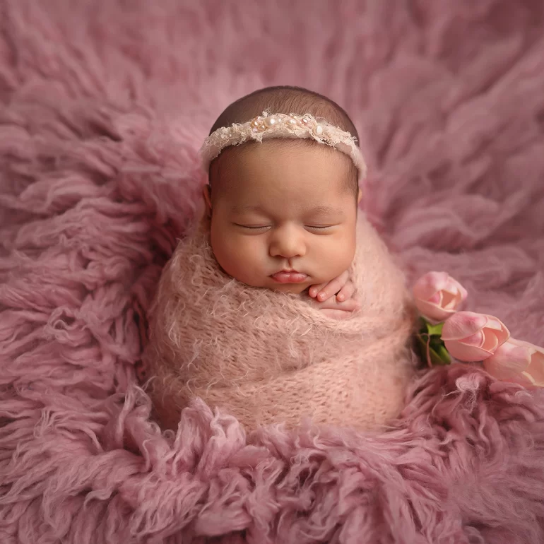 Newborn Photoshoot in North West London 6 Baby in pink knit on fluffy backdrop with pearl headband and tulips.
