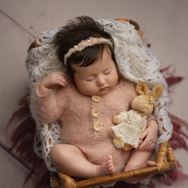 Newborn Photoshoot in North West London 33 Baby in pink knit with buttons, floral headband and bunny in wicker basket.