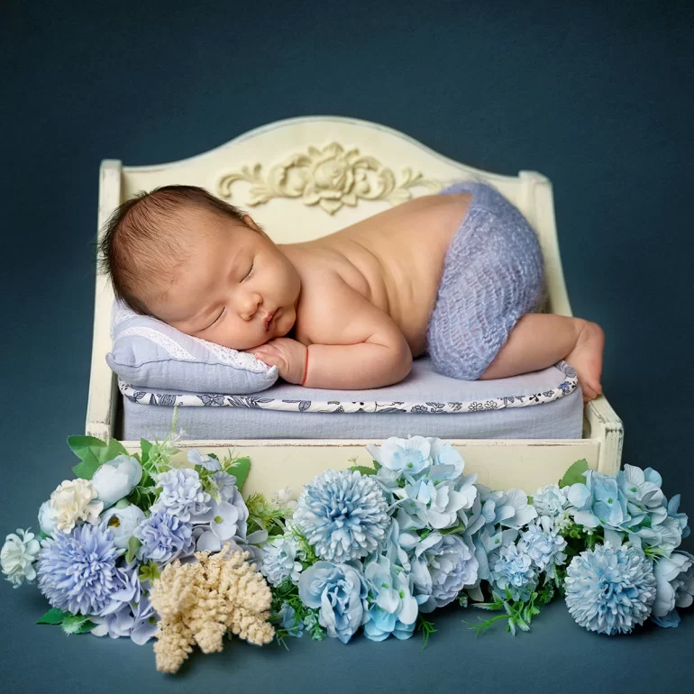 Newborn Photoshoot in North West London 10 Baby on vintage cream bed in blue wrap; lace pillow and soft florals.