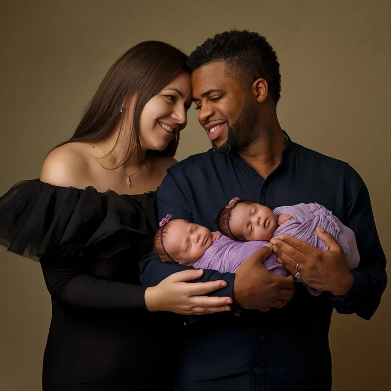 Newborn Photoshoot in North West London 74 Parents with twin girls in lavender wraps; mother in black, father in navy.