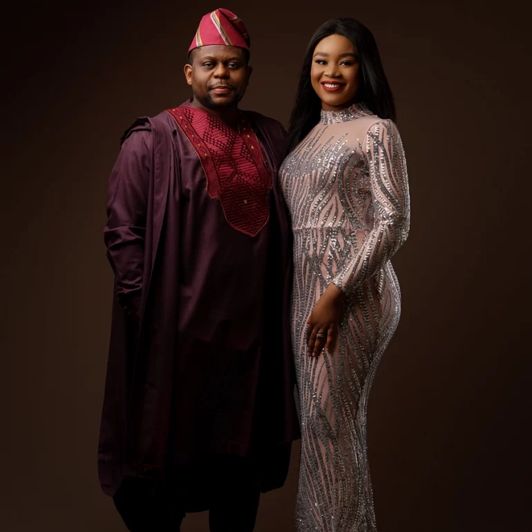 Family & Portrait Photoshoot in North West London 30 Man in maroon attire with cap and woman in silver patterned dress; dark studio backdrop.