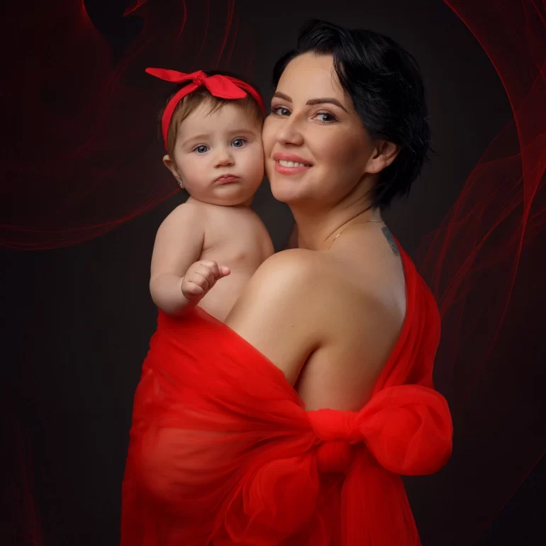 Family & Portrait Photoshoot in North West London 33 Mother in red bow wrap holding baby with red headband; black background with red swirls.