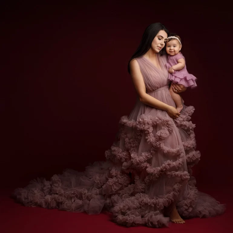 Family & Portrait Photoshoot in North West London 39 Mother in mauve ruffled gown holding smiling baby in matching outfit; burgundy backdrop.