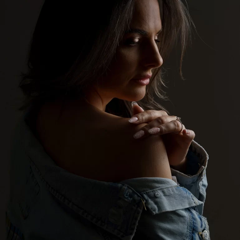 Family & Portrait Photoshoot in North West London 34 Woman in off‑shoulder denim jacket, side profile in soft, moody light.