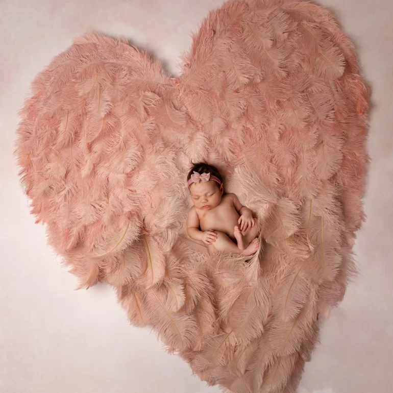 Newborn Photoshoot in North West London 43 Baby in blush feather heart with bow headband; dreamy, soft gradient.