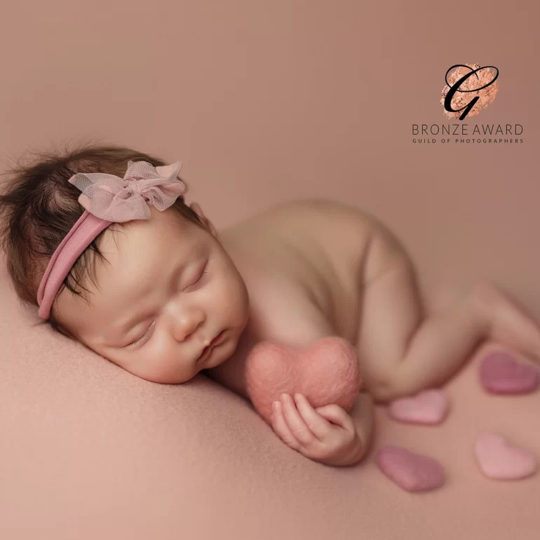 Newborn Photoshoot in North West London 2 Sleeping baby on pink with felt hearts and bow headband; dreamy look.