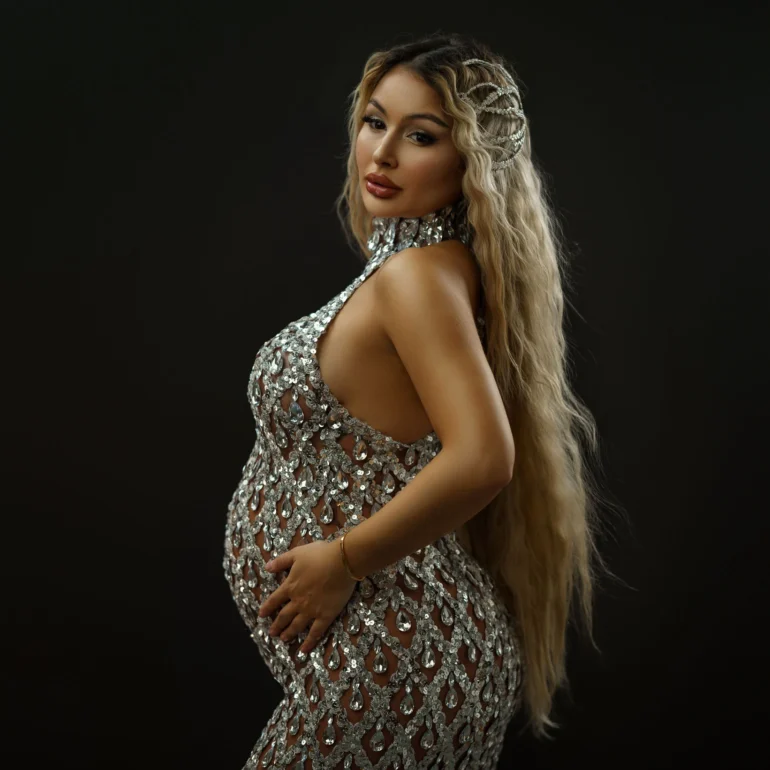 Maternity Photoshoot in North West London 79 Silver sequin gown; long wavy hair with delicate accessories; confident gaze.