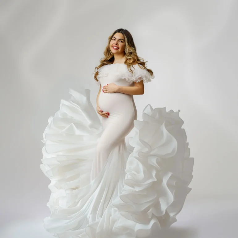 Maternity Photoshoot in North West London 81 Flowing white off‑shoulder gown with dramatic ruffles; joyful smile.