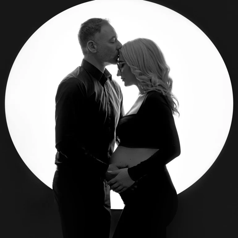Maternity Photoshoot in North West London 89 B&W couple with forehead kiss; dramatic circular backlight.
