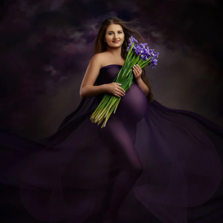 Maternity Photoshoot in North West London 92 Flowing purple gown with iris bouquet; moody cloud backdrop.