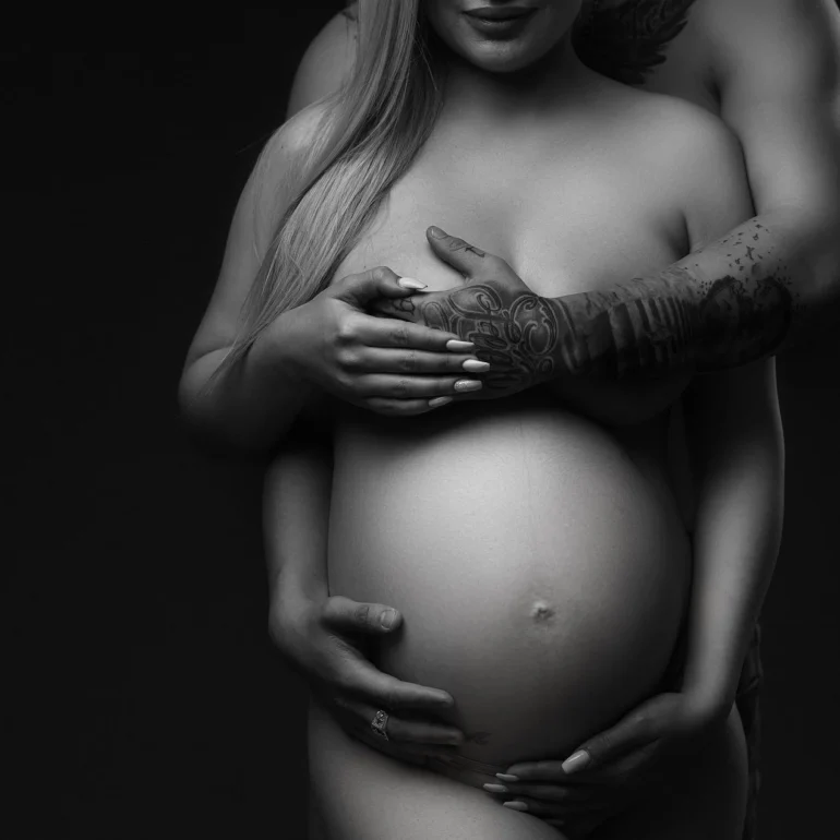 Maternity Photoshoot in North West London 90 Close‑up B&W embrace; tattooed arms and hands over belly.