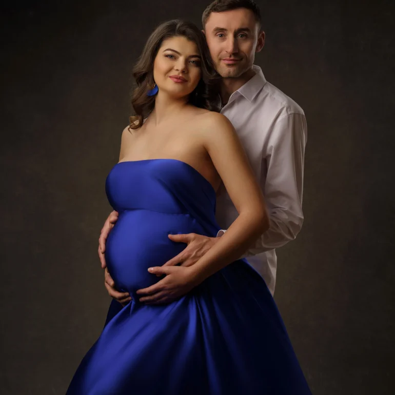 Maternity Photoshoot in North West London 76 Royal‑blue strapless gown; tender embrace from behind; warm light.