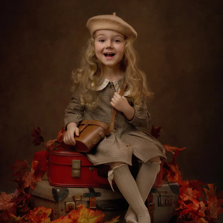 Family & Portrait Photoshoot in North West London 21 Blonde girl in vintage outfit on stacked suitcases with autumn leaves; studio set.