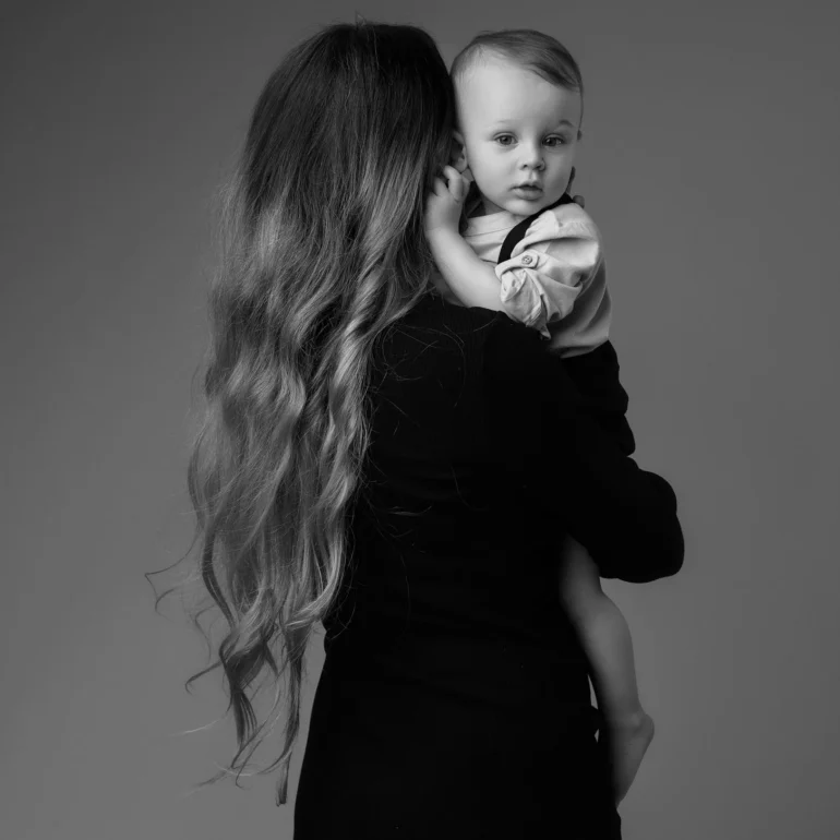 Family & Portrait Photoshoot in North West London 56 Mother with long wavy hair holding baby close; intimate black‑and‑white studio portrait.