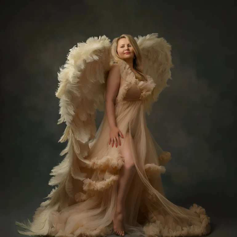 Family & Portrait Photoshoot in North West London 42 Woman in beige gown with feathered wings standing on reflective studio floor; moody backdrop.