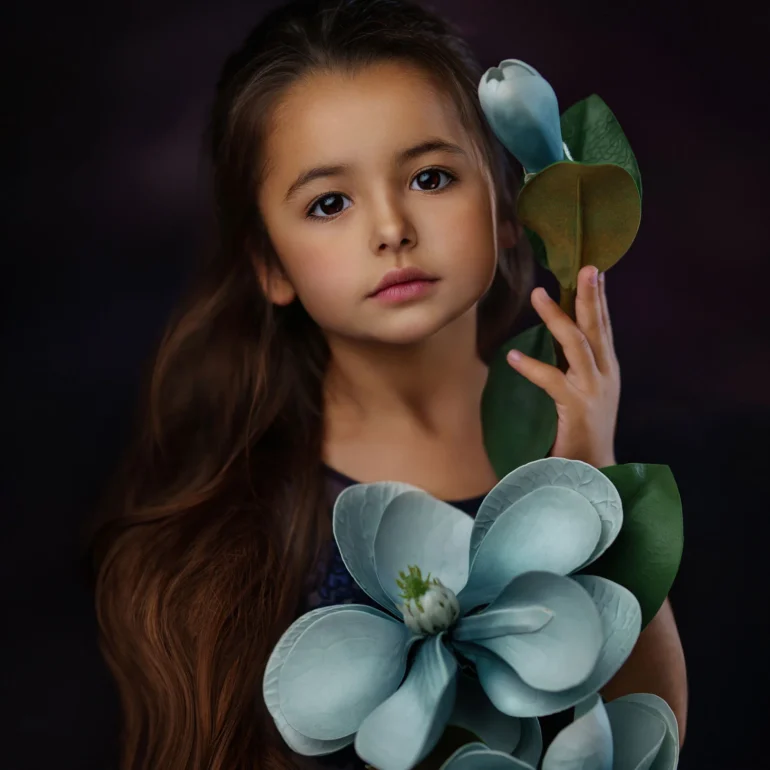 Family & Portrait Photoshoot in North West London 1 Young girl holding blue flowers against a dark, moody backdrop.