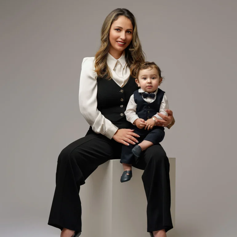 Family & Portrait Photoshoot in North West London 59 Smiling mother in formal outfit seated with young son in vest and bow tie; neutral studio.