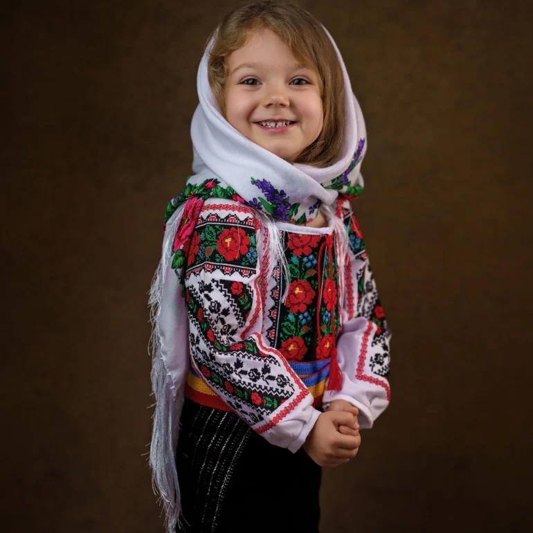 Family & Portrait Photoshoot in North West London 58 Young girl in embroidered traditional outfit with white scarf; warm studio backdrop.